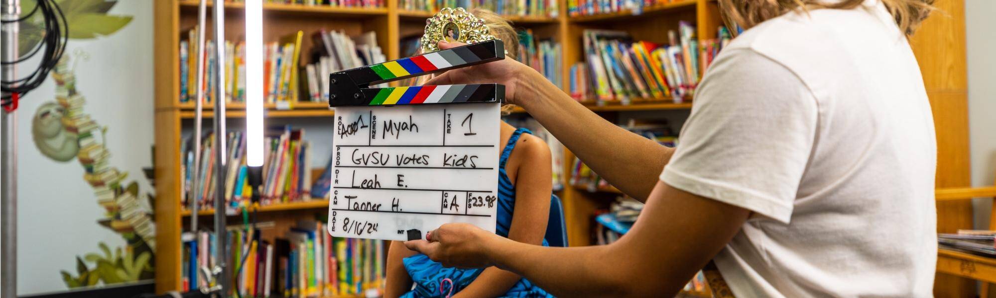 A student holding a slate on set